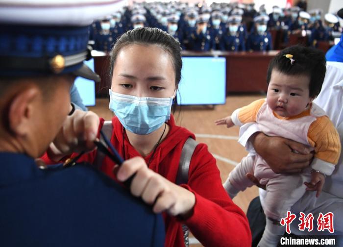 新消防員楊振的妻子彭莉與女兒現(xiàn)場見證丈夫加入“火焰藍(lán)”的神圣時(shí)刻。　劉忠俊 攝